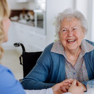Seniorin lacht Pflegerin an
