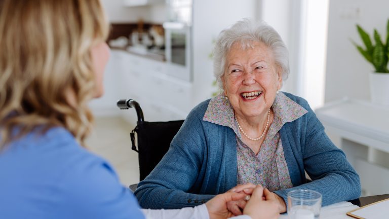 Seniorin lacht Pflegerin an
